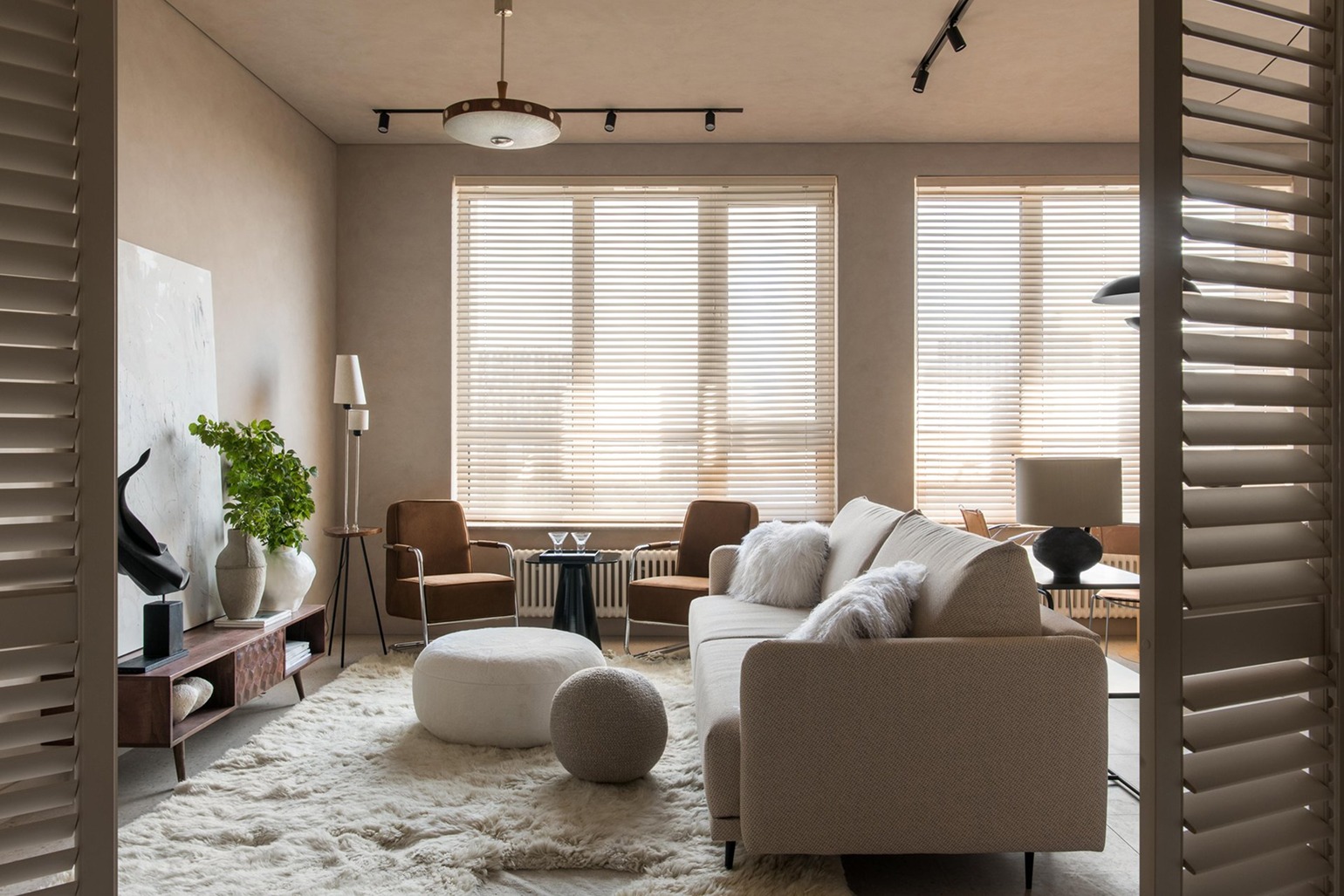 Japandi интерьер гостиной с естественным светом, трековым освещением и деревянными жалюзи