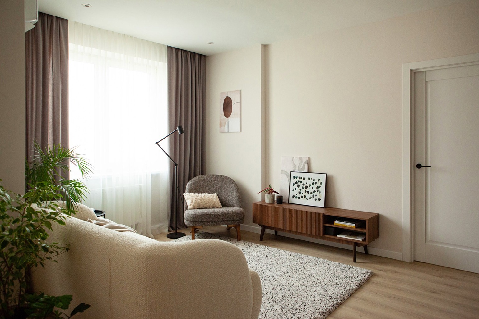 Интерьер джапанди фото: уютная гостиная с легкими шторами, ковром и деревянной мебелью